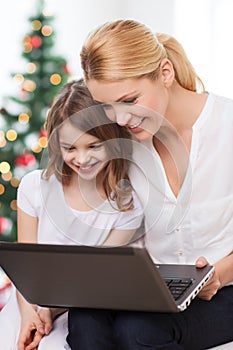 Smiling mother and little girl laptop computer