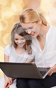 Smiling mother and little girl with laptop