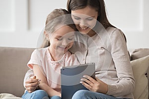 Smiling mother and little daughter using tablet computer together