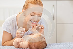 Smiling mother looking at her baby lying on bed