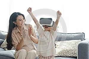 Smiling mother looking son playing games using virtual reality headsetVR at home. Technology future concept