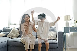 Smiling mother looking son playing games using virtual reality headsetVR at home. Technology future concept