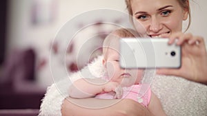 Smiling mother making selfie photo with baby girl. Woman with kid mobile photo