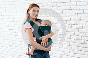 Smiling mother with newborn baby in baby sling.