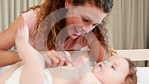 Smiling mother playing with baby son in his crib