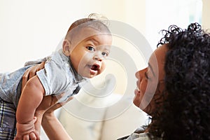 Smiling Mother Playing With Baby Son At Home