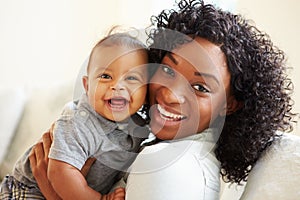 Smiling Mother Playing With Baby Son At Home