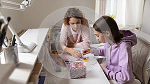 Smiling mother playing colorful boardgame with adolescent daughter.
