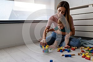 Smiling mother playing with her cute toddler son at home