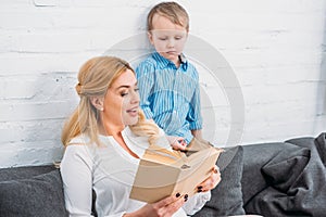 Smiling mother reading book to little