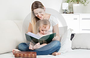 Smiling mother reading story to her 9 months old baby boy