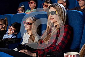 Smiling mother sitting with little daughter in cinema