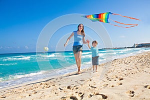 Smiling mother and son holding arms with kite