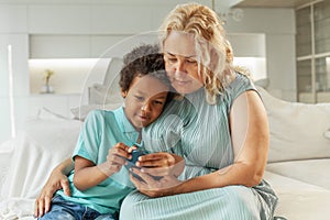 Smiling mother teaching her son to use gadgets and posting photos in social networks