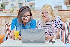 Smiling mother and teenage daughter looking into laptop screen together