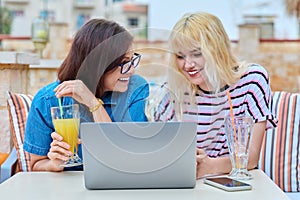 Smiling mother and teenage daughter looking into laptop screen together