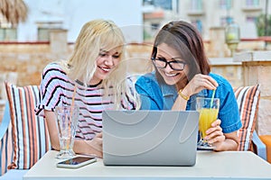 Smiling mother and teenage daughter looking into laptop screen together