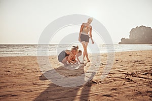 Smiling Mother watching her kids playing on a sandy beach