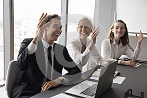 Smiling motivated businesspeople raising hands, make common unanimous decision