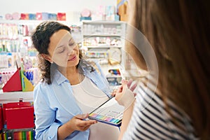 Smiling multi-ethnic woman holding metal case with colored pencils, shopping for school stationery in creative art store