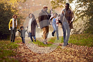 Smiling Multi-Generation Family Having Fun With Children Walking Through Autumn Countryside Together