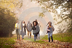 Smiling Multi-Generation Family Having Fun With Children Walking Through Autumn Countryside Together