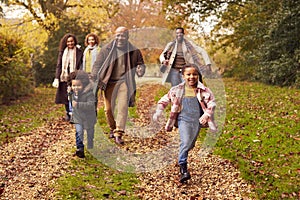 Smiling Multi-Generation Family Having Fun With Children Walking Through Autumn Countryside Together