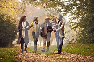 Smiling Multi-Generation Family Having Fun With Daughter Walking Through Autumn Countryside Together