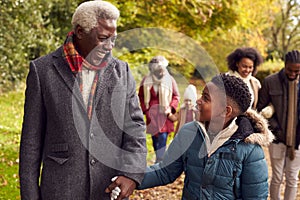 Smiling Multi-Generation Family Having Fun Walking Through Autumn Countryside Together