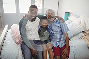 Smiling multi-generation family sitting together on bed