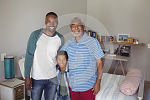 Smiling multi-generation family standing together in bedroom