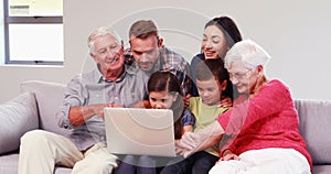 Smiling multi generation family using laptop