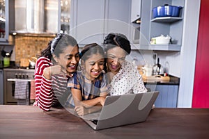 Smiling multi-generation family using laptop in kitchen