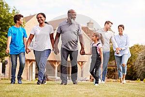 Smiling Multi-Generation Mixed Race Family Walking In Garden At Home