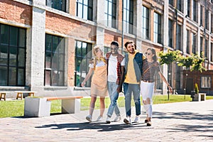 smiling multicultural group of friends hugging while walking