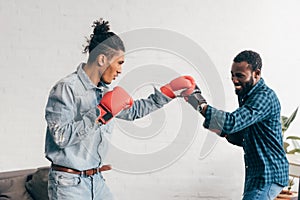 smiling multicultural male friends doing sparring in boxing