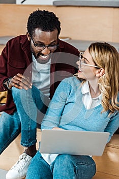 Multicultural students in glasses using laptop in lecture hall