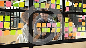 Smiling multiethnic colleagues brainstorm working with sticky notes