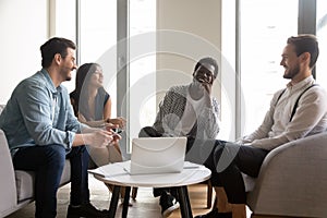 Smiling multiethnic colleagues laugh cooperating at office meeting