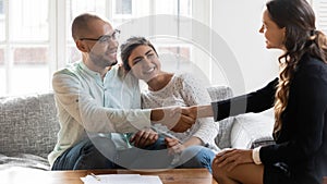 Smiling multiethnic couple handshake realtor greeting at meeting