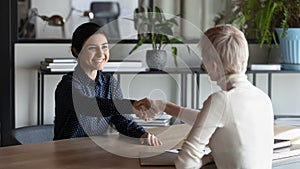 Smiling multiethnic female partners handshake at meeting