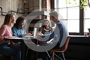 Smiling multiethnic friends have fun studying in cafe together