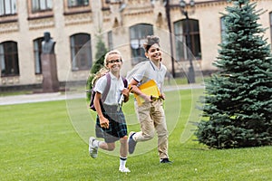 Smiling multiethnic schoolkids with notebooks running