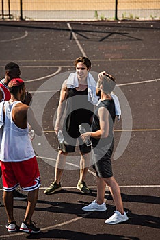 Smiling multiethnic sportsmen with water and