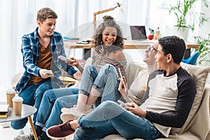 smiling multiethnic teenagers sitting on sofa