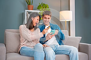 Smiling multiethnic young couple shopping online with credit card and smartphone inside