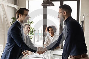 Smiling multiracial businessmen handshake at meeting in office