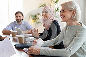 Smiling multiracial colleagues discuss ideas at office meeting