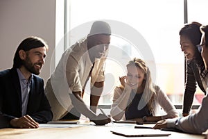 Smiling multiracial colleagues discuss paperwork at meeting