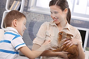 Smiling mum and little son with pet rabbit